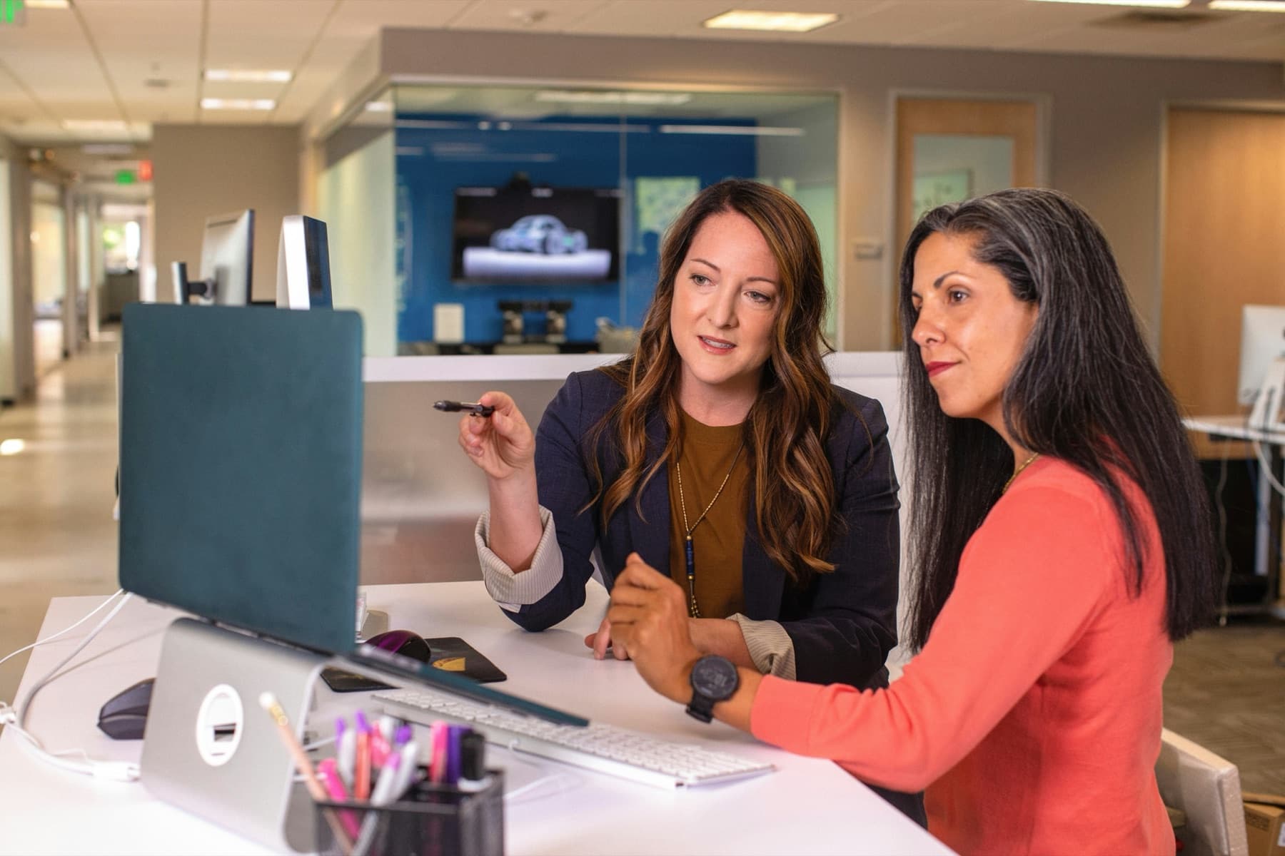 Two colleagues looking at a screen together in an open office